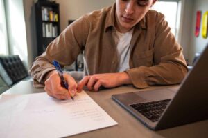 Businessman writing on paper at desk in office