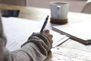 Person writing with a blue pen on paper